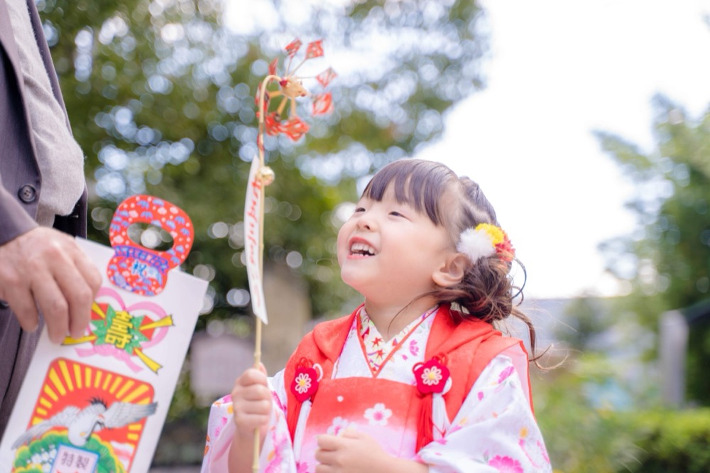 千歳飴を手に笑う七五三の女の子