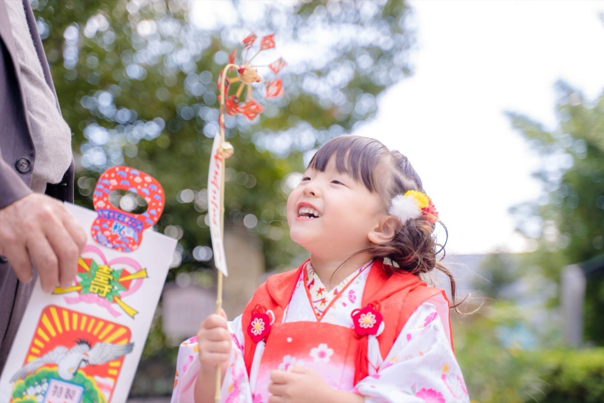 千歳飴を持って笑う七五三の女の子
